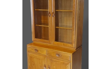 An Ercol Windsor side cabinet with two glazed doors enclosin...
