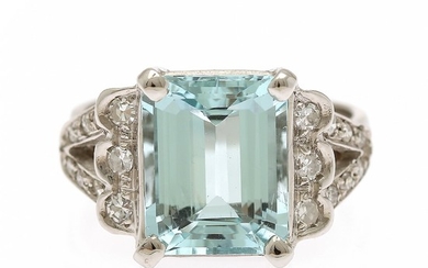 An aquamarine and diamond ring set with an emerald-cut aquamarine flanked by numerous single-cut diamonds, mounted in 18k white gold. Size 56.