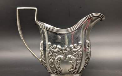 An early 20th century silver cream jug with embossed floral ...