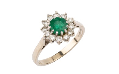 An emerald and diamond cluster ring, the central circular emerald...