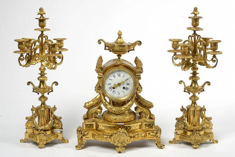 Garniture de cheminée trois pièces Napoléon III en bronze doré comprenant une pendule et une paire de candélabres à quatre bras de lumière. Mouvement à lame. Epoque: XIXème. (* à l’élément sommital de la pendule). H.:+/- de 43,5 à 52cm.