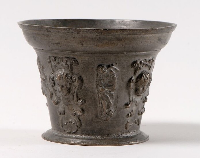 Mortar made of bronze with a scaled decoration of four heads of winged angels alternating with two busts of the pope in profile and two allegorical figures. Period XVIIe siècle. An eight-sided marble base is attached to it. H : 10,5 cm and D. sup :...