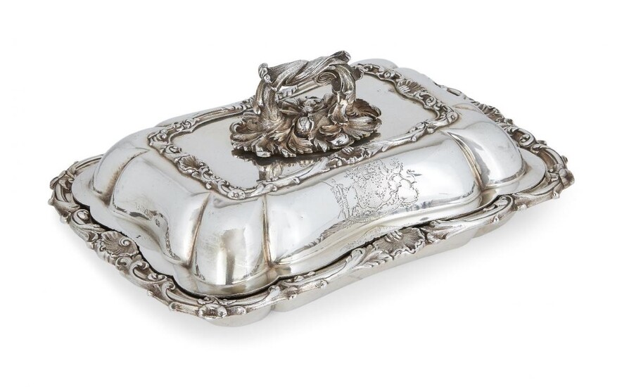 A George IV silver entrée dish and cover, London, c.1829, William Ker Reid, of rectangular form, with applied shell and foliate scroll rim, the cover with foliate twist handle and engraved armorial to two sides, the motto reading 'non sine...