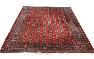 A Pakistani Bokhara red ground carpet, mid 20th century, with central repeating gull motifs, on a red ground, contained repeating borders, 360cm x 302cm Provenance: The Geoffrey and Fay Elliot collection.