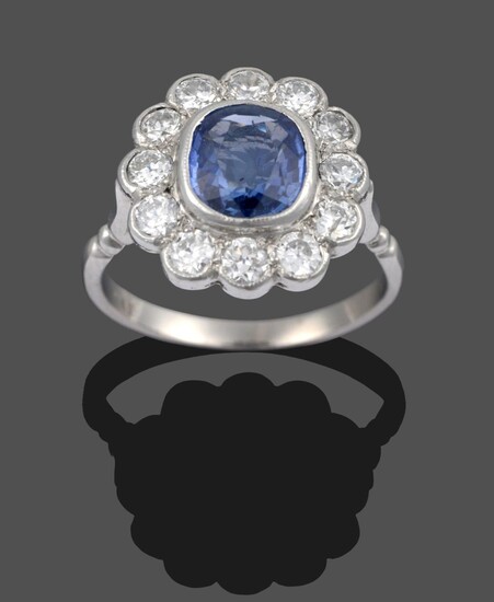 A Sapphire and Diamond Cluster Ring, the cushion cut sapphire within a border of round...
