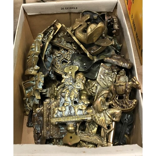 A box containing a collection of various brass door knockers...