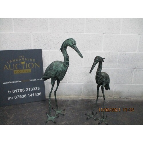 A pair of metal garden storks with bronze effect finish