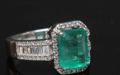 A white gold emerald and diamond cluster ring