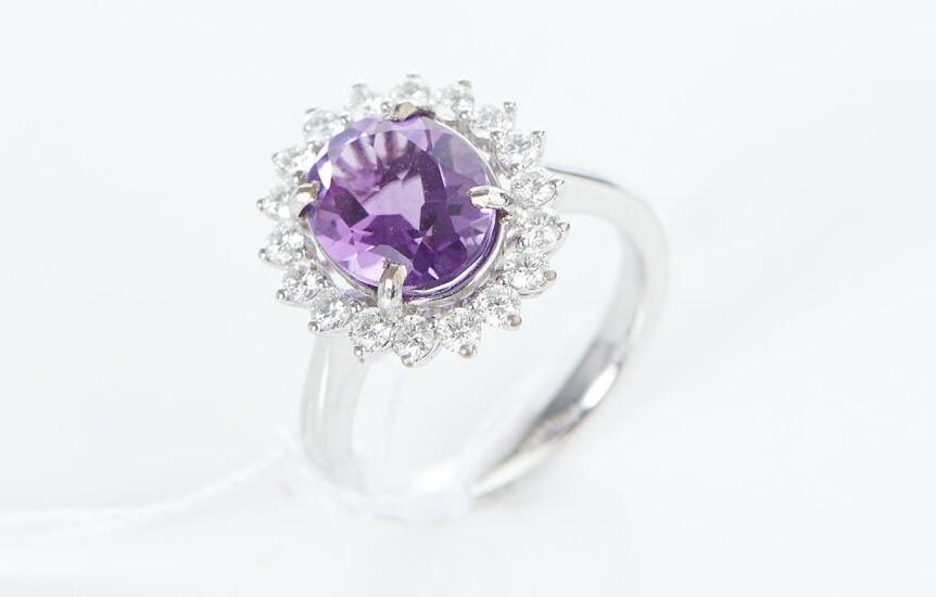 AN AMETHYST AND DIAMOND CLUSTER RING IN 18CT WHITE GOLD, THE OVAL CUT AMETHYST WEIGHING 2.45CTS, WITHIN A SURROUND OF DIAMONDS TOTA...