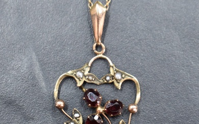 An Edwardian yellow metal pendant stamped 9ct having garnet and split pearl decoration on a yellow