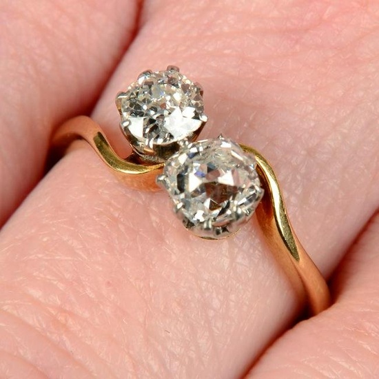 An early 20th century 18ct gold old-cut diamond two-stone crossover ring.Estimated total diamond