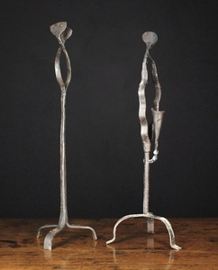 Two 18th Century Style Peerman with sprung rush holders on crossed wavy straps above tripod bases. One 23¾ in (60 cm) high, the other with a conical candle socket emanating from the stem, 23 in (58 cm) high.