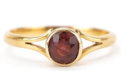Unmarked gold garnet solitaire ring with split shoulders, te...