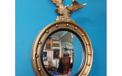 Victorian giltwood convex mirror surmounted by eagle. {63 cm...