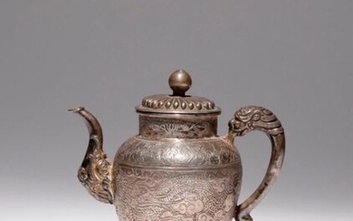 A TIBETAN REPOUSSE AND INCISED SILVER EWER AND COVER 19TH...