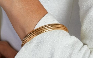 A gold bangle by PIAGET.