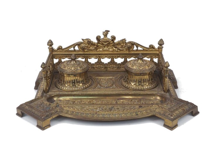 A late Victorian gilt bronze inkstand, late 19th century, with pierced gallery, recessed pen tray centred by a portrait medallion and twin glass-lined inkwells with hinged lids, 33cm wide