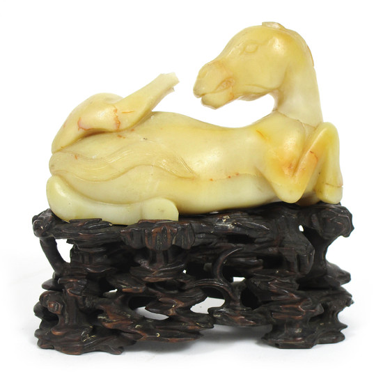 A pale grey-yellow stone carved horse on wood stand
