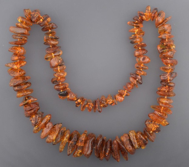 An Amber Necklace, ninety-five irregular shaped and sized orangey-brown amber...