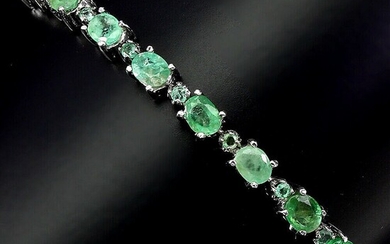 An emerald bracelet set with numerous oval and circular-cut emeralds, mounted in rhodium plated sterling silver. Adjustable length.