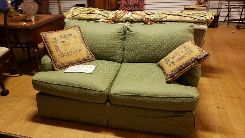 Green upholstered love seat with 2 embroidered pillows