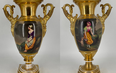 Manifattura del secolo XIX. Coppia di vasi biansati in porcellana dipinta in policromia con figure e paesaggi entro riserva su…