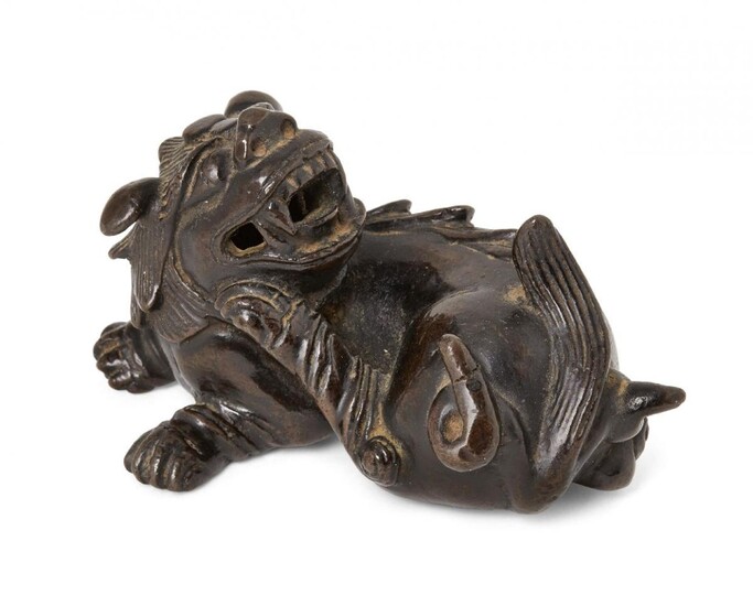 Property of a Gentleman (lots 36-85) A Chinese bronze scroll weight, Ming dynasty, 17th century, cast as a recumbent lion dog with its head raised looking back over its body, 9cm long