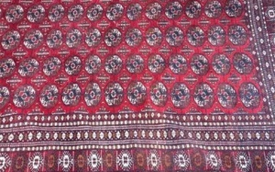 An old Afghan fringed wool rug the blood red ground populated with geometric medallions in concentric borders, 300 x 185...