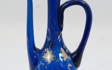 A Bohemian blue glass ewer, 19th century, the body with gilt highlights and gilded grape and vine decoration, lacking a cover, 26.5cm high