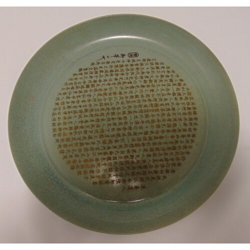 A Chinese celadon glazed dish carved with Chinese calligraph...