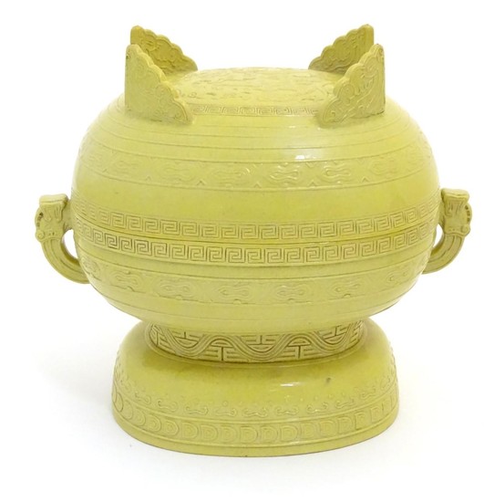 A Chinese yellow ground lidded pot raised on a foot, with tw...