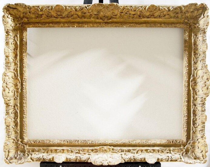 A Gilded Composition Louis XIV Style Frame, early-mid 20th century, with leaf sight, sanded frieze, the cross-hatched ogee with foliate and flower head scrollwork, shell cartouche centres and corners, and shell demi-centres, 55 x 78 cm (sight): A...