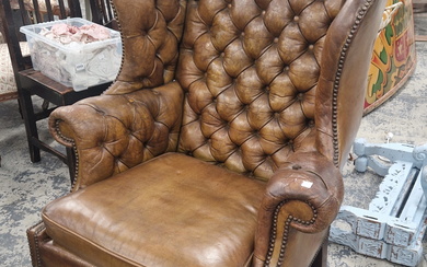 A LEATHER UPHOLSTERED MAHOGANY WING ARMCHAIR, THE ARMS AND BACK BUTTONED AND CLOSE NAILED