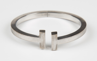 A Tiffany & Co white gold oval sprung bangle with T-form terminals, detailed 'Tiffany &
