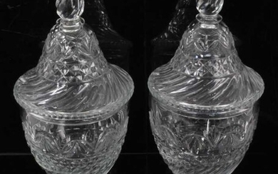 A pair of Regency cut glass covered urns or bonbonnieres, with bands of fluting, diamond and foliate patterns, on square stepped lemon squeezer bases, 31cm high