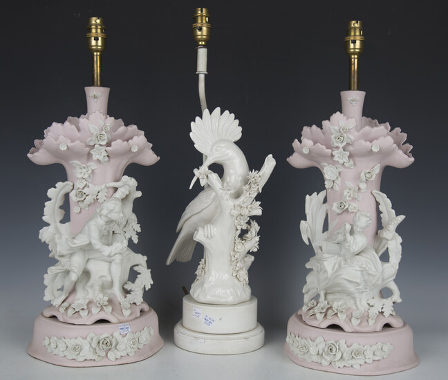 A pair of bisque porcelain table lamps, modelled as a lady and gallant seated beside trees, height 4
