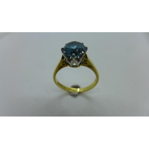 An 18ct gold and blue stone ring, possibly topaz, in a round...