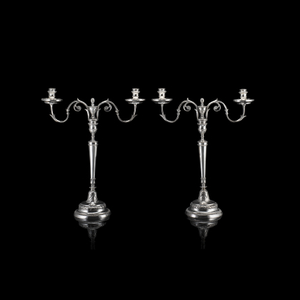 Gruppo di quattro candelieri in metallo argentato due con portacandele sagomati e decorati a fiori e volute (difetti)