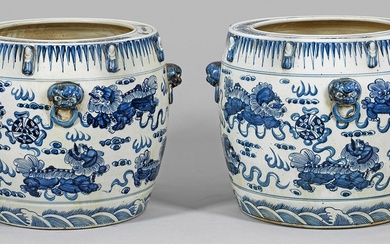 Paire de cache-pots monumentaux bleu et blanc en porcelaine. Corps en forme de tonneau orné...