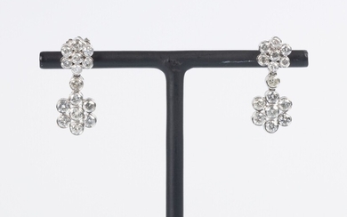 Paire de pendants d'oreilles en or gris à décor de deux fleurs serties de diamants...