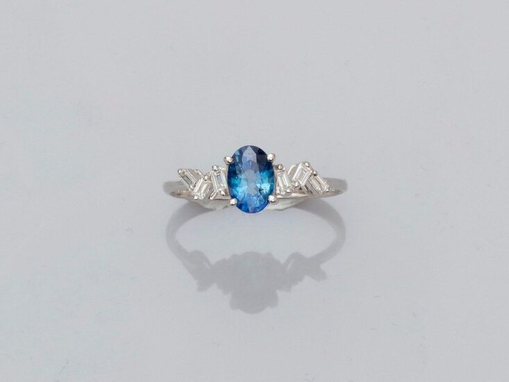 Ring in white gold, 750 MM, set with an oval sapphire weighing 1.05 carat and supported by two garlands of baguette-cut diamonds, 16 x 7 mm, size: 54, weight: 1.95gr. rough.