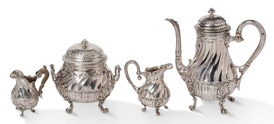~Silver torso-rimmed service consisting of a teapot with an ivory ringed handle, a sugar bowl and a milk jug in the form of a baluster with a rocaille decoration of post friezes and acanthus leaves, resting on four scrolled feet. Goldsmith's illegible...
