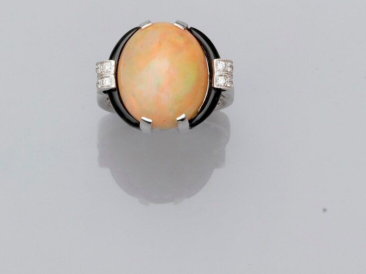 White gold ring, 750 MM, decorated with a cabochon opal weighing about 7 carats between two onyx motifs and two diamond bars, total dimensions 19 x 16 mm, opal , size : 54, weight : 7,9gr. rough.
