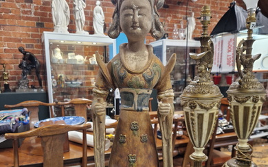A TANG STYLE POTTERY FIGURE OF A LADY STANDING HOLDING PEGS IN EACH HAND, HER DRESS GLAZED IN OCHRE