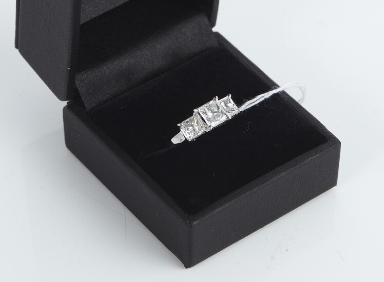 A THREE STONE DIAMOND RING IN 18CT WHITE GOLD, CENTRALLY SET WITH A PRINCESS CUT DIAMOND OF 1.05CT, SHOULDERED BY PRINCESS CUT DIAMO...