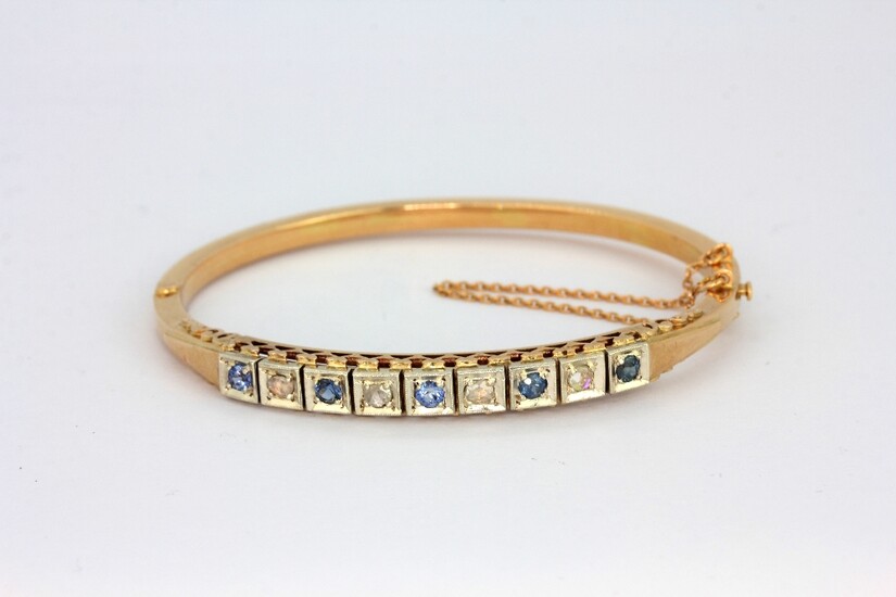 A hallmarked 14ct yellow and white gold bangle set with rose cut diamonds and sapphires, L. 6.5cm.