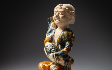 A sancai-glazed figure of a foreigner holding a 'goose' wine vessel, Tang dynasty | 唐 三彩藍釉抱鵝壺俑