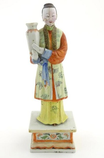 An Oriental porcelain model of a male figure wearing a
