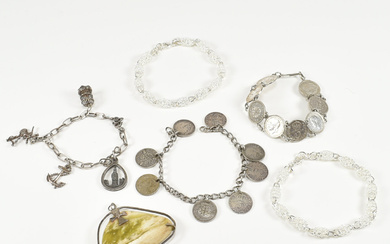 An assorted collection of silver jewellery. The lot to include two 925 marked fancy link chain bracelets united by lobster claw clasp, two coin bracelets, green stone & cross necklace pendant & a charm bracelet with charms. All items test as silver...