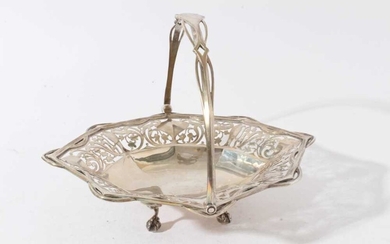 Good quality Edwardian silver cake basket of oval form with faceted and pierced decoration and swing handle, raised on four claw and ball feet (London 1906)
